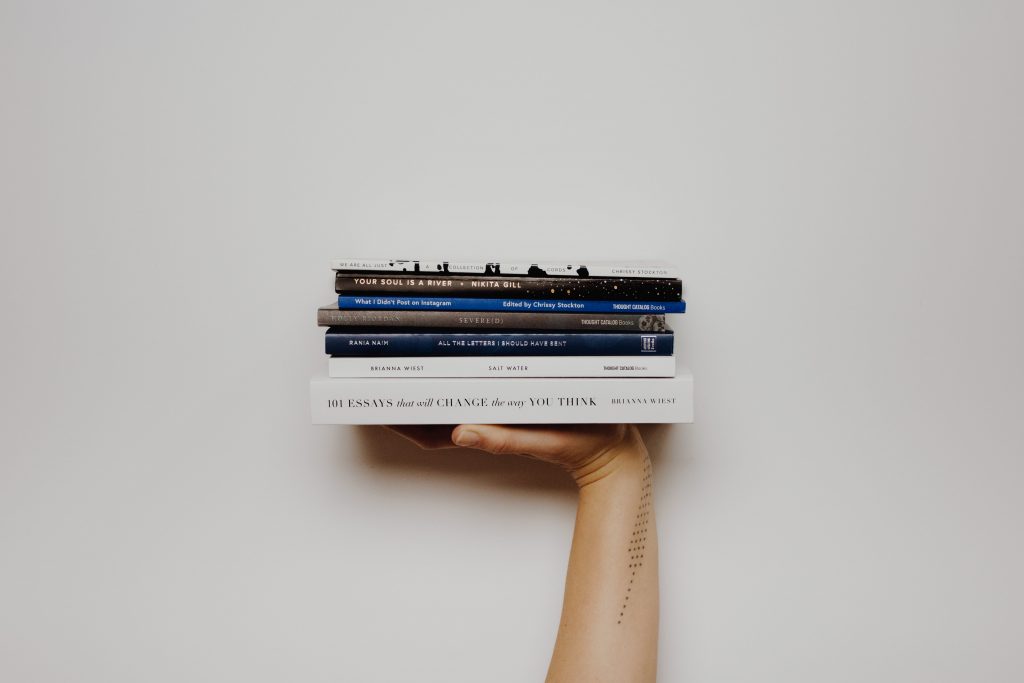 persons arm holding pile of books