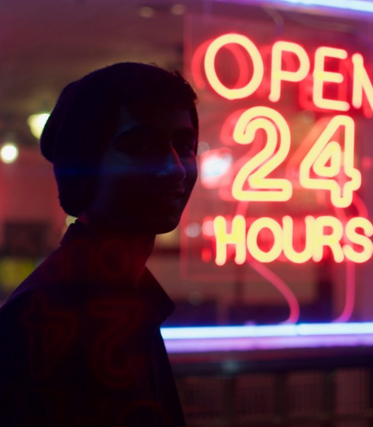 Person standing in front of sign with text "open 24 hours"