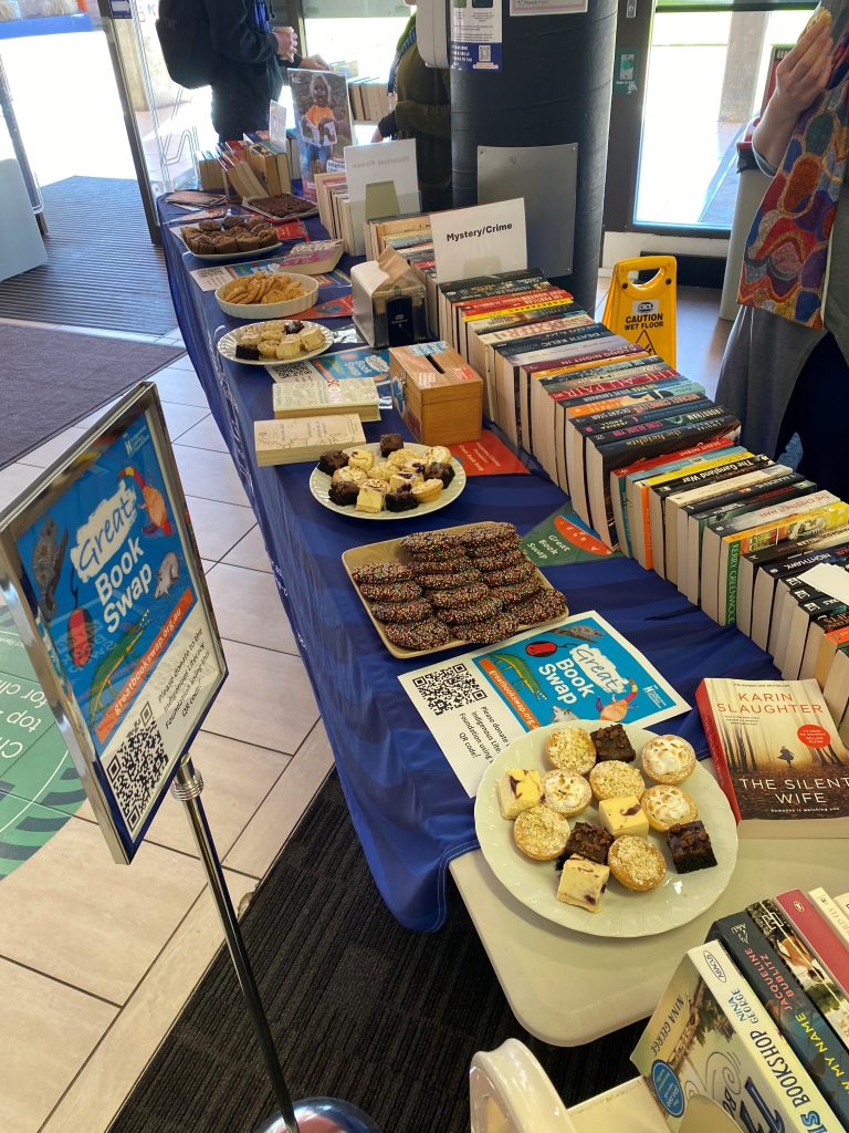 Table with books and plates of cakes and biscuits.