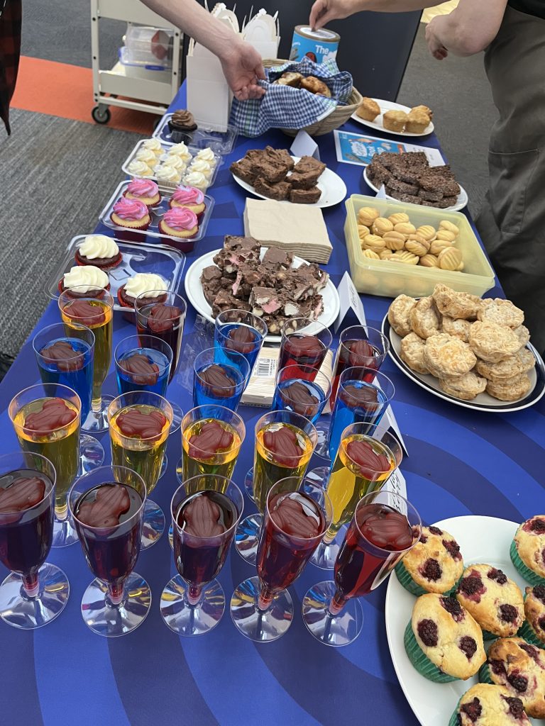 Table displaying cakes, slices and cups of jelly with lolly frogs on top.