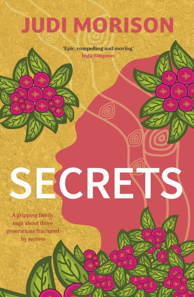 A stylized book cover featuring the silhouette of a head filled with swirling decorative patterns against a textured gold background. Bright pink and green botanical illustrations frame the design. The title Secrets appears in large white letters, with the author’s name, Judi Morison, displayed at the top.